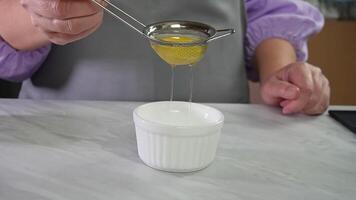 Person straining egg yolks using mesh kitchen sieve over white bowl.step 3 video