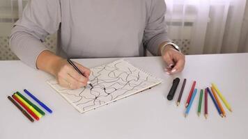 Artistic process of coloring intricate patterns with multicolored pencils on white desk video