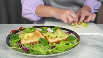 Preparing avocado toast on artisan bread with fresh greens in kitchen setting video