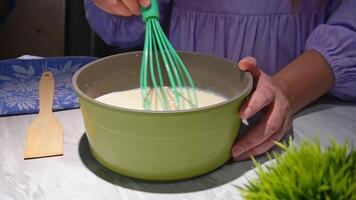 Mixing batter with green whisk in green bowl - home baking preparation video