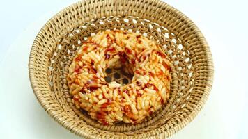 High angle view of round rice cracker with cane sugar syrup in bamboo tray rotated on white background. video