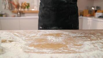 A person in an apron is standing in front of a table with flour video