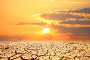 A dramatic landscape of parched earth with deep cracks, set against a fiery sunset, evokes a sense of vulnerability, change photo