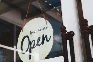 Rustic Open Sign Hanging on Glass Door of a Small Business Shop Inviting Customers Inside on a Sunny Day photo