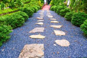 Serene Garden Pathway with Stone Steps Surrounded by Lush Greenery and Vibrant Foliage in a Tranquil Outdoor Setting photo