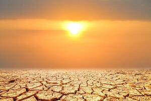 A dramatic landscape of parched earth with deep cracks, set against a fiery sunset, evokes a sense of vulnerability, change photo