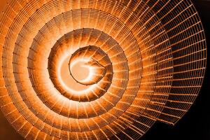 Abstract spiral with glowing red and orange tones and wire texture against a black background, symbolizing energy, motion, industrial and futuristic design concepts. Copy space photo