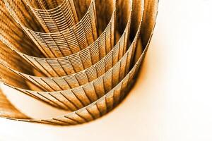 Abstract spiral metal coiled wire mesh with orange brown grid pattern, geometric symmetry, minimalist design for industrial construction, diy concepts. Isolated on white background. Copy space photo