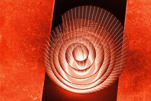 Abstract spiral with glowing red and orange tones and wire texture against a black background, symbolizing energy, motion, industrial and futuristic design concepts. Copy space photo
