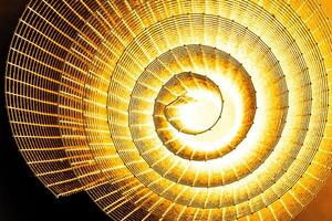 Abstract spiral with glowing yellow wire texture against a black background, symbolizing color contrast, energy, motion, industrial and futuristic design concepts. Copy space photo