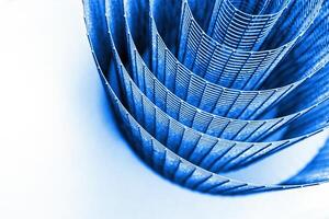 Abstract spiral metal coiled wire mesh with blue grid pattern, geometric symmetry, minimalist design for industrial construction, diy, architectural concepts. Isolated on white background. Copy space photo