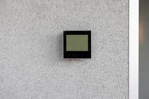 Electronic thermostat mounted on white wall displaying current indoor temperature. Device is sleek, modern, and essential for climate control in a minimalist environment. photo