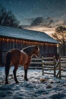 A horse stands in the snow near a rustic barn, illuminated by soft lights at sunset. photo