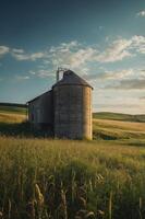 A rustic silo beside a weathered barn, surrounded by golden fields under a blue sky. photo