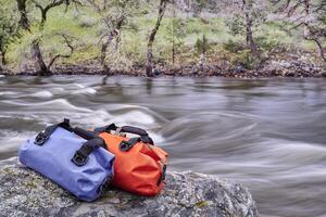 small waterproof duffels on a river shore photo