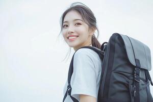 A woman with a backpack smiles while standing photo