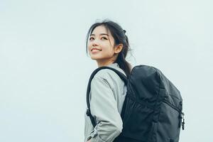 Asian woman with backpack standing on gray background photo