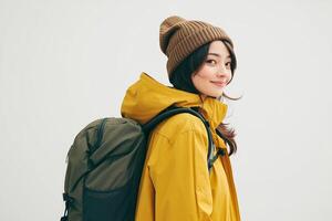 Portrait of young asian woman with backpack and yellow raincoat isolated on white background photo