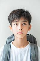 A young boy with a backpack looking at the camera photo
