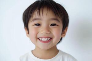 A little boy smiles while standing in front of a white background photo
