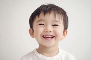 A young boy smiles while standing in front of a white background photo
