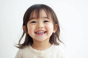 A little girl smiles while standing in front of a white background photo