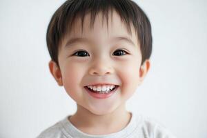 A young boy smiles while standing in front of a white background photo