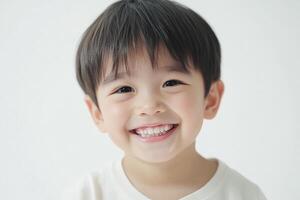 A young boy smiles while standing in front of a white background photo