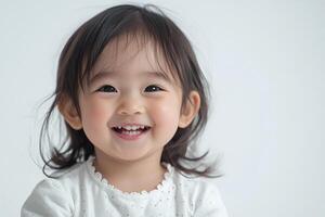 A little girl smiles while standing in front of a white background photo