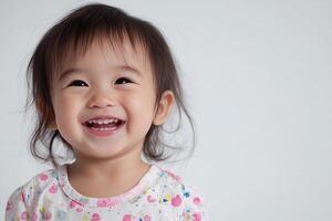 A little girl smiles while standing in front of a white background photo
