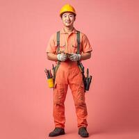 A man in an orange overalls and hard hat holding a tool photo