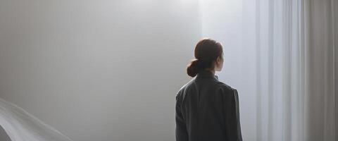 A woman standing in front of a window with a curtain photo