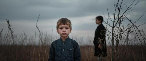 A boy and a woman standing in a field photo