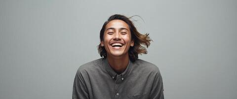 A man is smiling while standing in front of a gray background photo