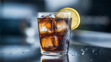 A glass of cola with ice and lemon on a table photo