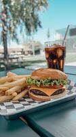 A hamburger and fries on a tray on a picnic table photo