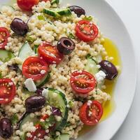 A plate of couscous salad with tomatoes, cucumbers and olives photo