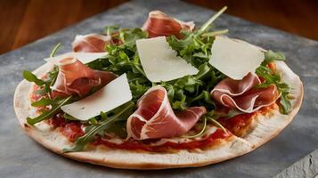 A pizza with meat and greens on a wooden table photo