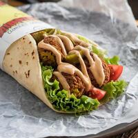 A wrap with meat and vegetables on top photo