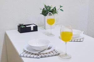 An Elegant Dining Table Setup with Bright Yellow Drinks and Fresh Greenery Accents photo