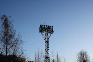 A tall sports field floodlight tower standing majestically against the clear blue sky above photo