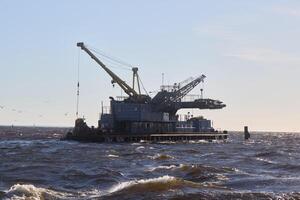 An Oil Rig situated in the vast Ocean with ongoing Crane Operations taking place photo
