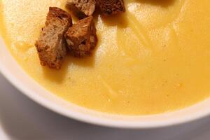 An inviting creamy soup served with croutons beautifully arranged on a white background photo