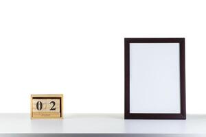 Wooden calendar 32 January with frame for photo on white table and background