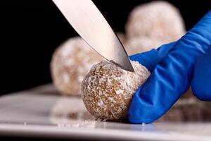 Beautiful sweets with coconut are cut with a knife on a white plate on a black background photo