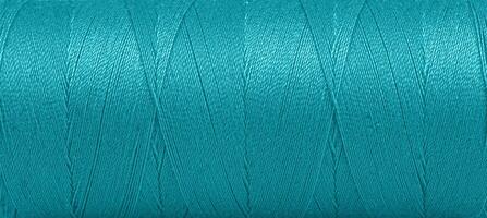 Texture of threads in a spool of turquoise color on a white background photo