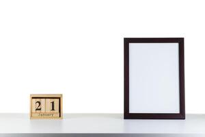 Wooden calendar 21 January with frame for photo on white table and background