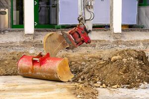 Excavator bucket collects soil and old asphalt at a construction site photo