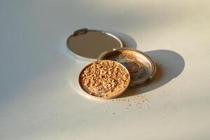 Broken palette with highlighter on a white table. Decorative cosmetics photo