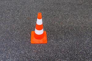 traffic cone, white and orange stripes on gray asphalt, copy space. Construction cones marking part of road with a layer of fresh asphalt. photo